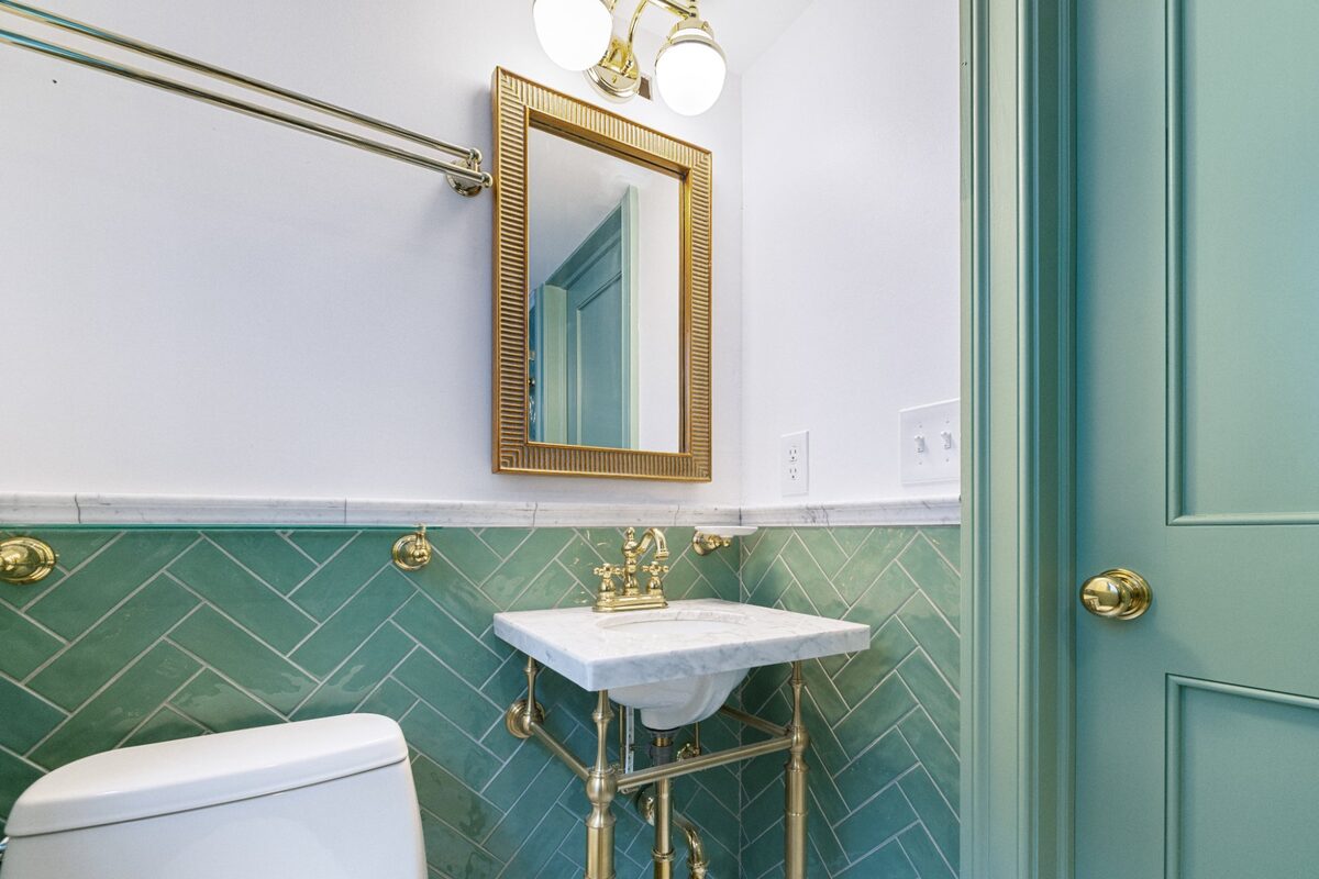 Vanity with reeded brass mirror and painted green door — Butler, MD