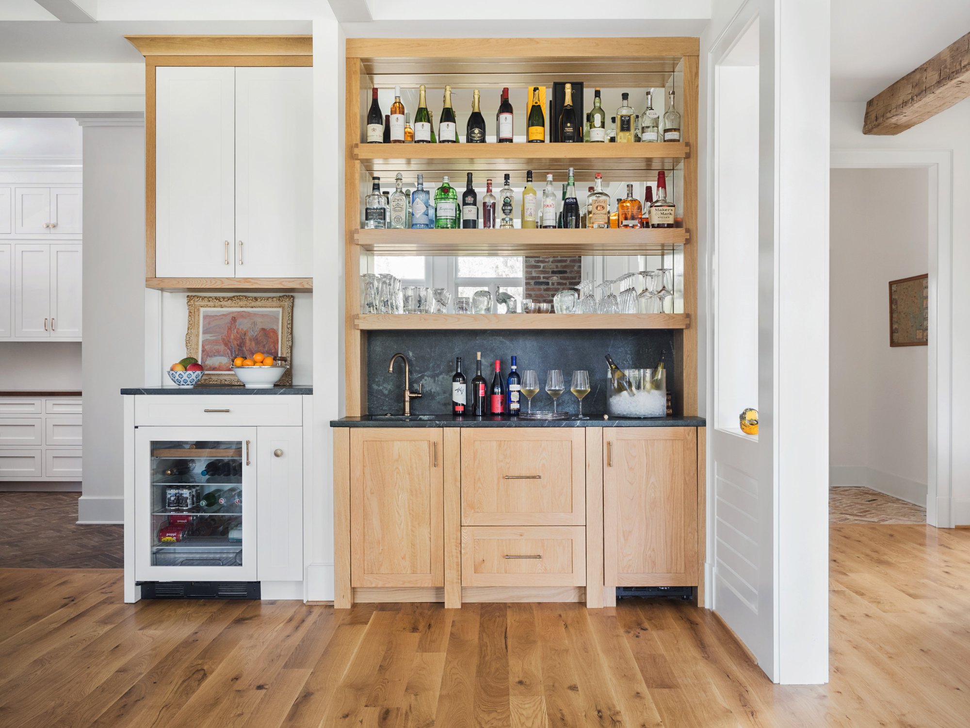 Built-in bar with natural oak cabinetry, soapstone counter and backsplash, open shelving with spirits, mirror back, and wine refrigerator — Nordic Farmhouse