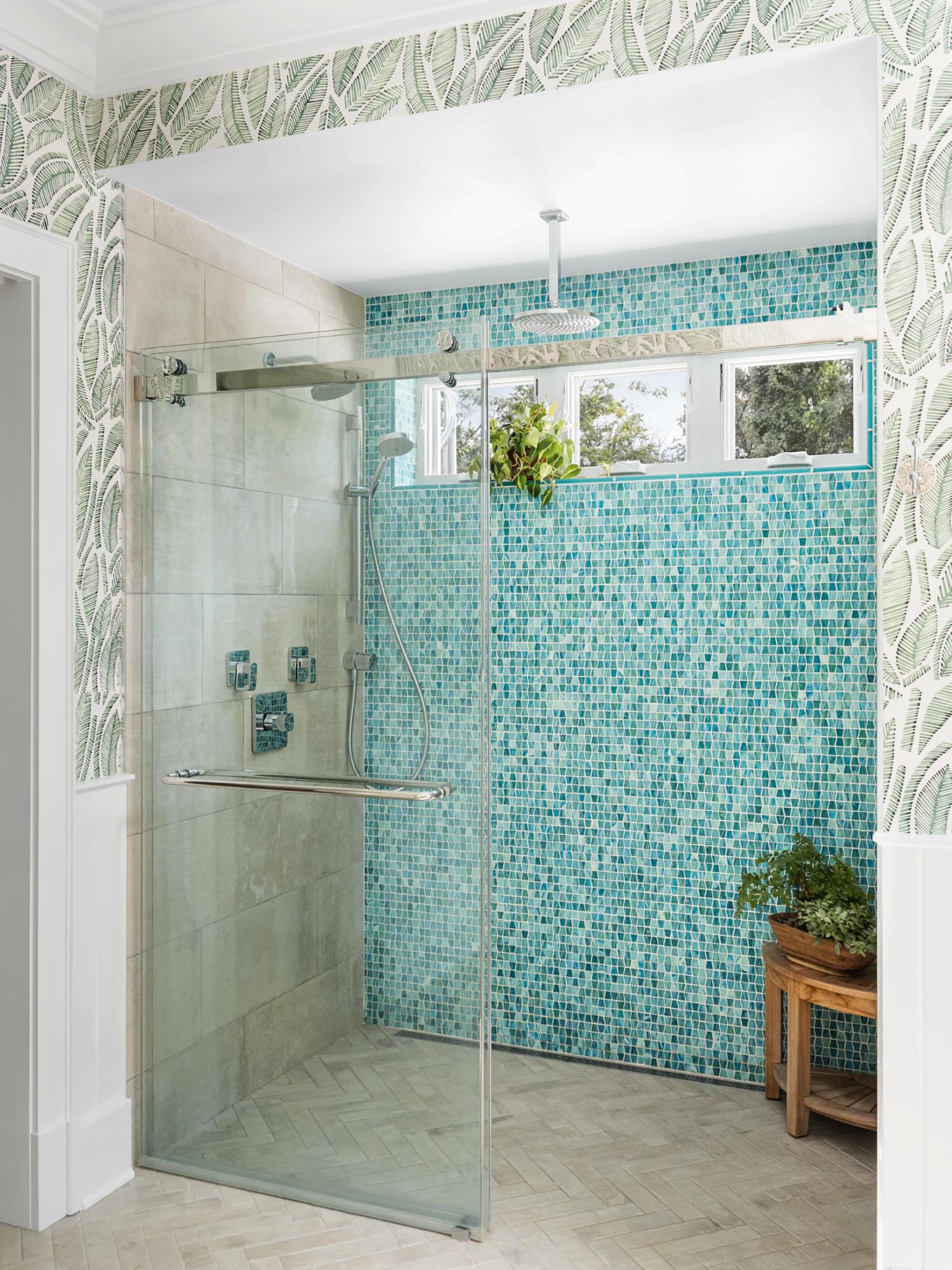 Walk-in shower with turquoise glass mosaic feature wall, rain head, hand shower, body jets, botanical wallpaper, and herringbone floor tile — Tropical Master Bath, Hunt Valley