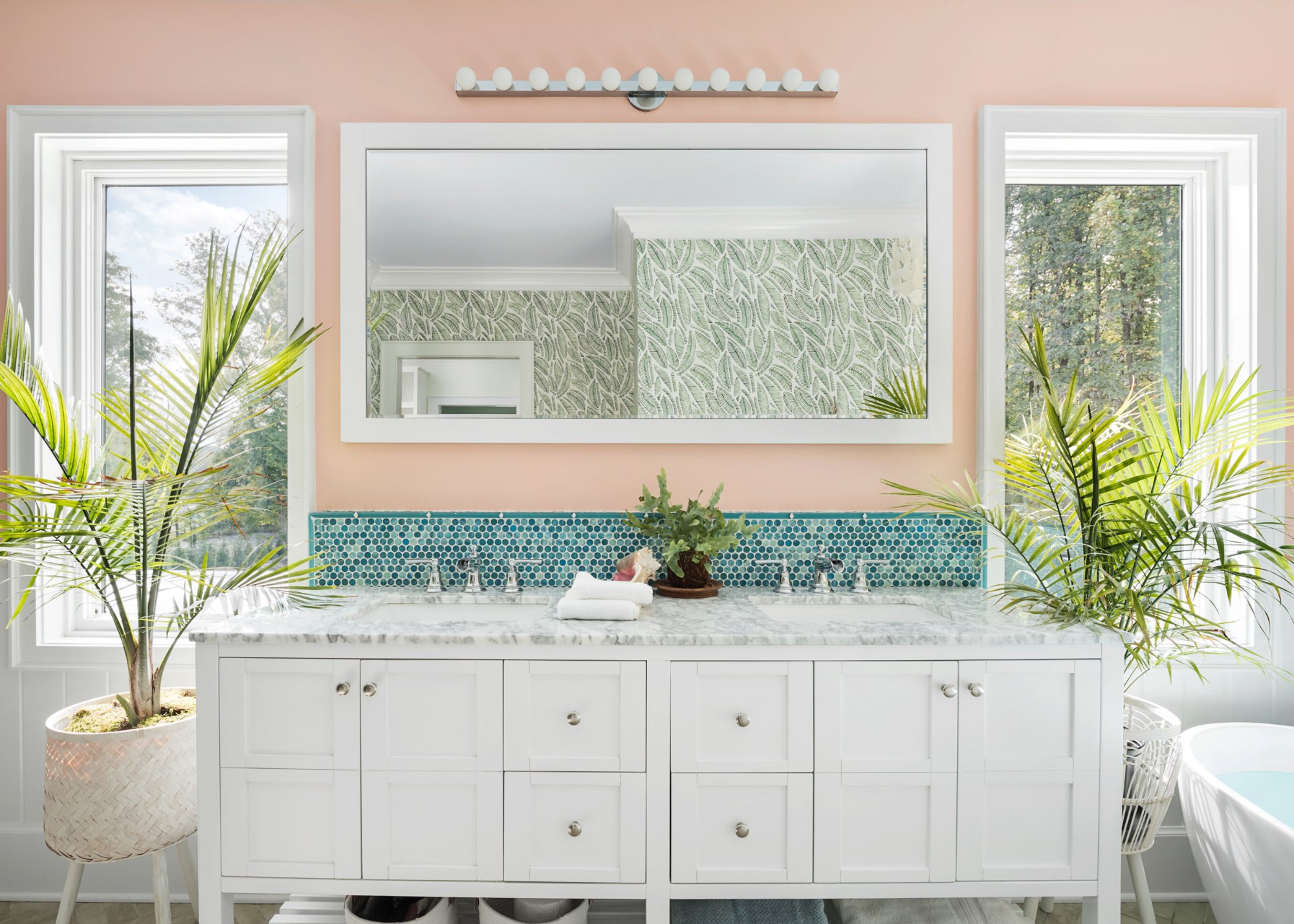 Double vanity with marble counter, turquoise penny round backsplash, peach walls, palm plants, and globe vanity light — Tropical Master Bath, Hunt Valley