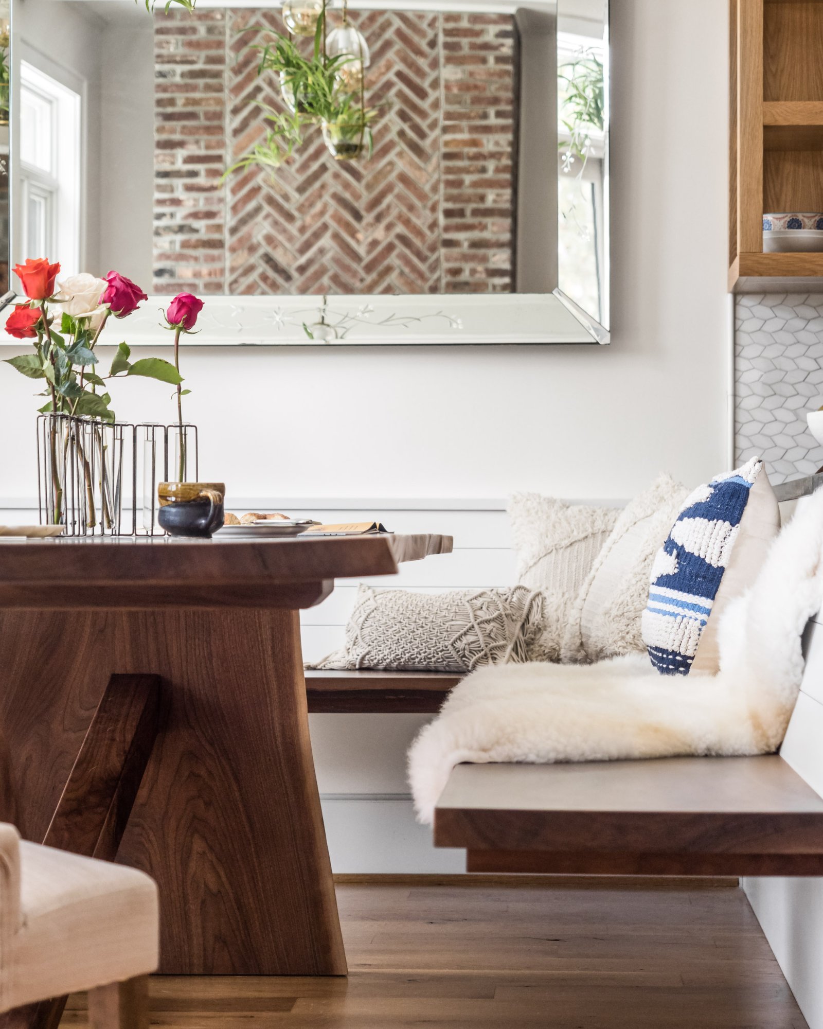 Dining nook with walnut trestle table, built-in bench with shiplap, sheepskin throws, and herringbone brick accent wall — Nordic Farmhouse