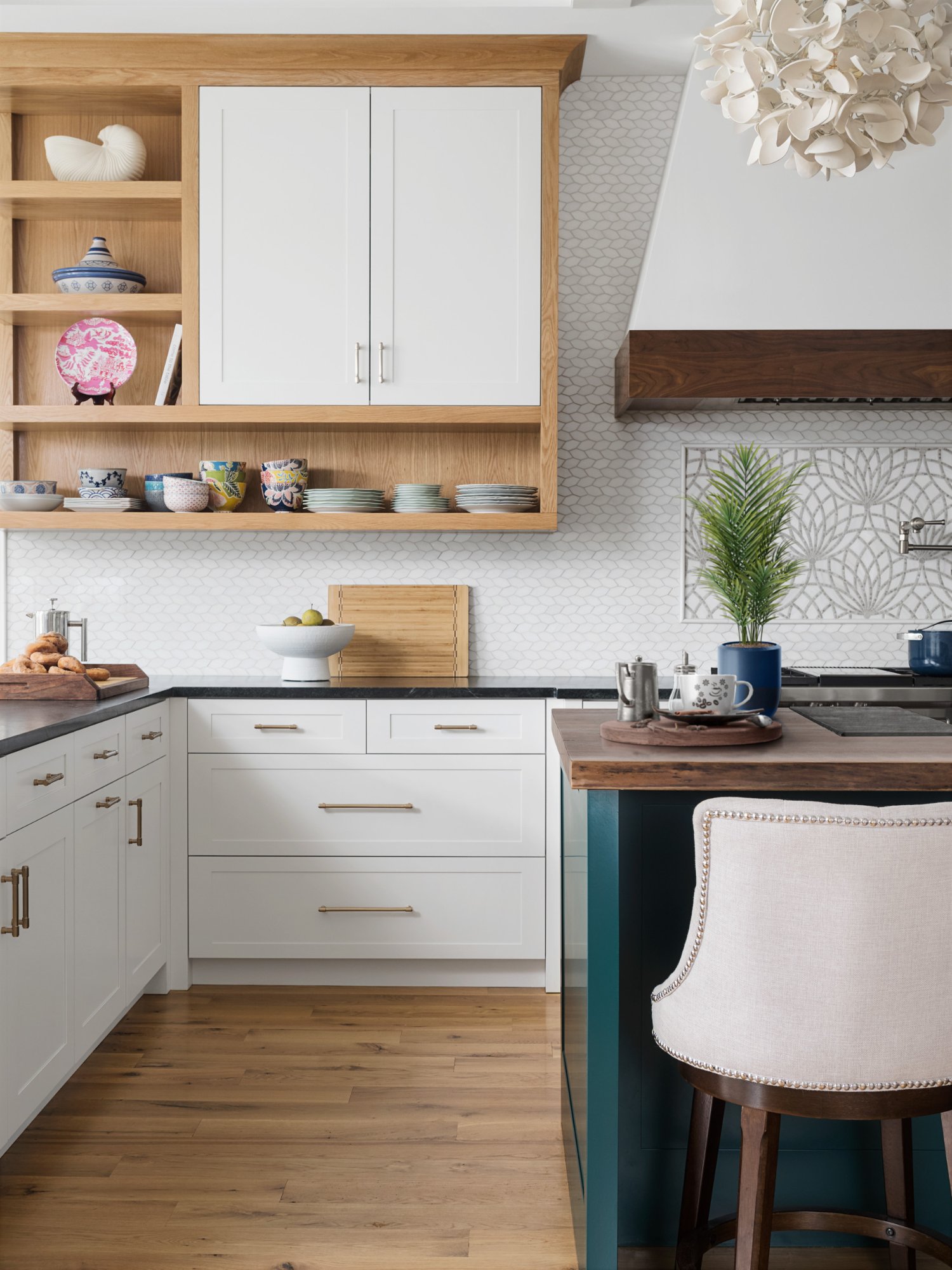 Kitchen corner showing white oak shelving with colorful ceramics, soapstone counters, brass hardware, and green island — Nordic Farmhouse