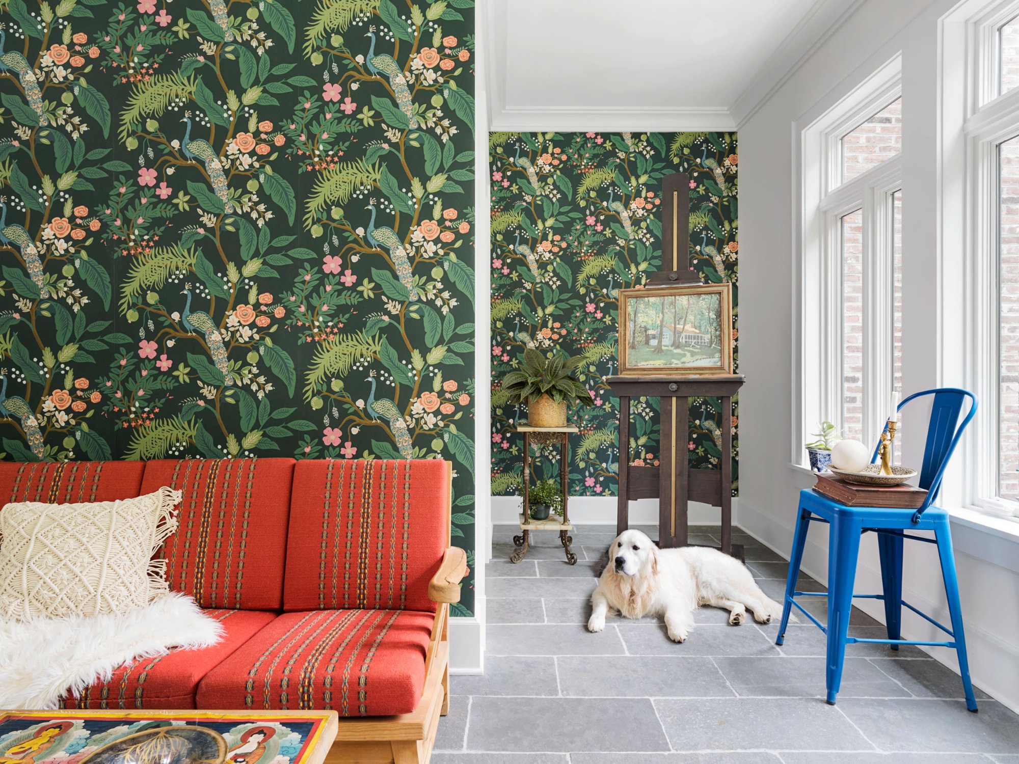 Sunroom with chinoiserie peacock wallpaper, bluestone floor, red midcentury daybed, and golden retriever — Nordic Farmhouse