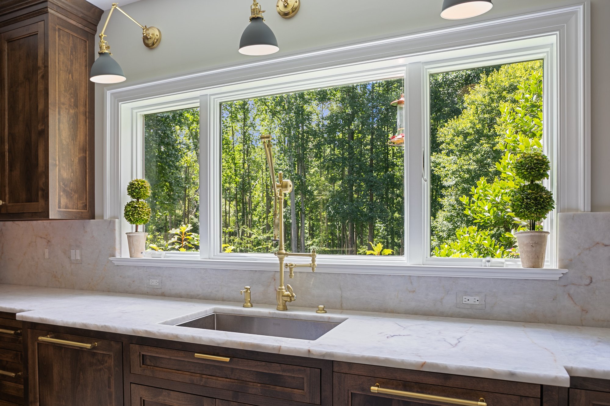 Sink window with brass pot filler, sconces, and topiaries — Monkton Farms