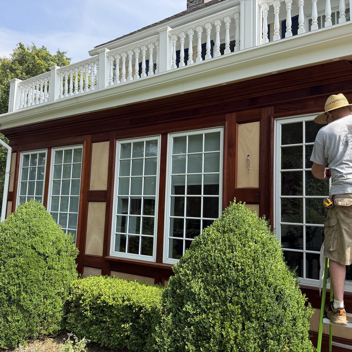 Carpenter on ladder fitting sapele casing window by window — North Winds Porch, Towson
