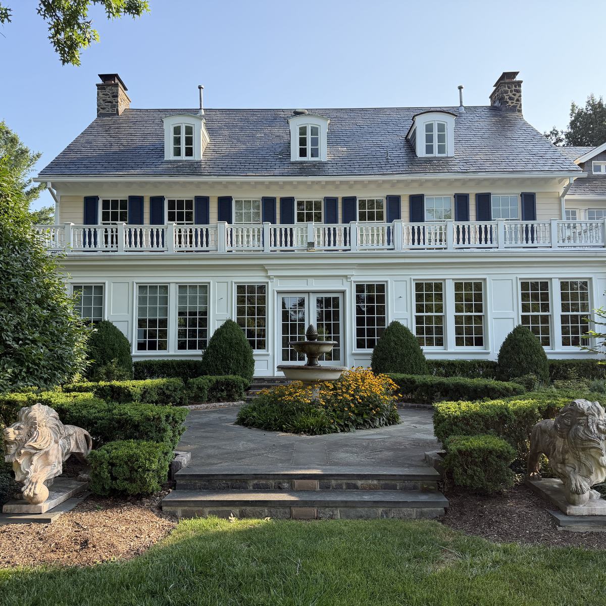 Full rear elevation of the restored home with porch, balustrade, and formal garden — North Winds Porch, Towson