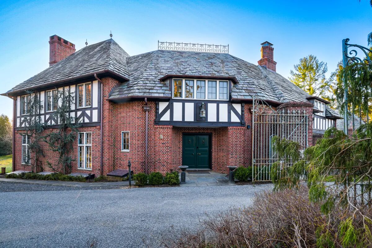 English Tudor gatehouse with slate roof, half-timbering, and green entry door — Hunt Valley, MD