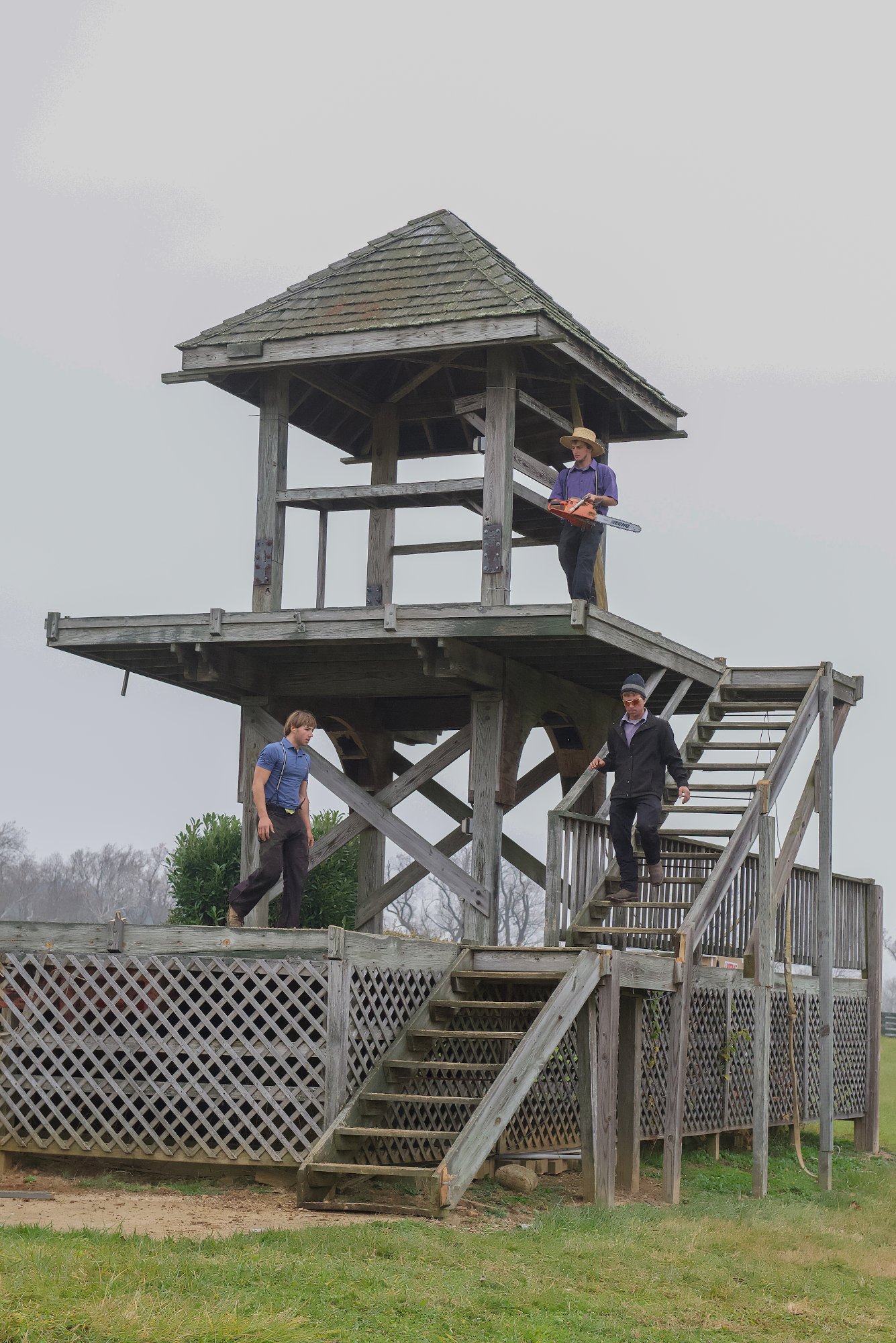 Crew with chainsaws preparing the old tower for demolition, full structure visible with shingle roof — Shawan Downs