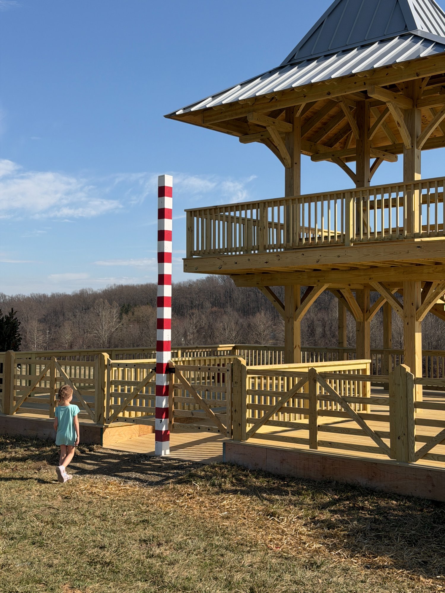 Ground-level view showing new pressure-treated fencing, gates, and tower base with rolling countryside beyond — Shawan Downs
